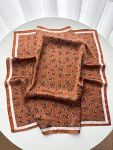 Detail of silk-like square scarf featuring vintage paisley patterns in caramel brown