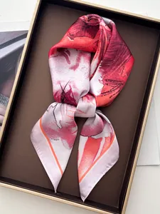 Detailed view of red floral silk scarf elegantly folded inside a premium gift box
