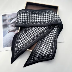 Close-up of elegant houndstooth silk scarf with geometric star patterns on a gold tray
