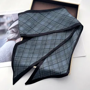 Detail of blue and gray checkered narrow silk scarf on a luxury golden display tray