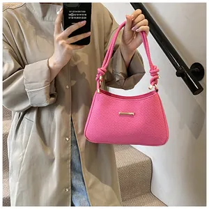 Detail of rose pink underarm bag with V-shaped embossing and knotted woven strap handle