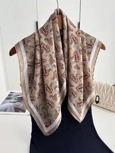 Close-up of vintage camel paisley silk scarf with white borders draped on a wooden hanger