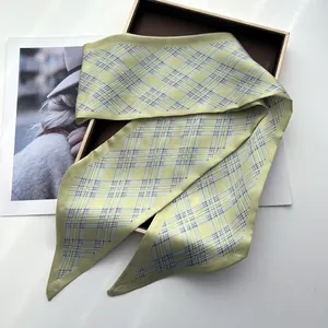 Detailed view of yellow-green silk scarf with classic plaid pattern in gift box