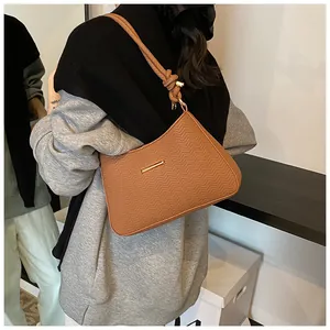 Detail of brown PU leather underarm bag featuring herringbone embossing and gold buckle