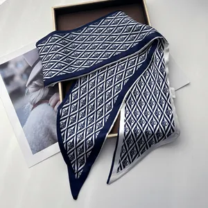Detailed close-up of navy and white geometric silk twilly scarf on a wooden tray