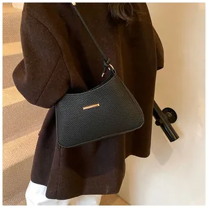 Detail of black underarm bag with V-shaped wave texture and gold rectangular buckle