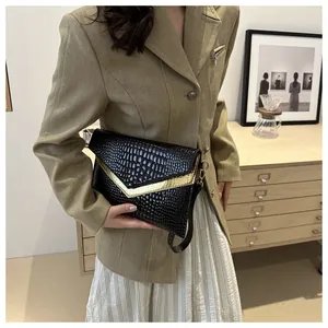 Detail of black crocodile texture bag featuring a golden V-shaped metal trim on flap