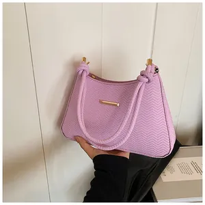 Detail of light purple underarm bag with V-shaped texture and golden metal hardware