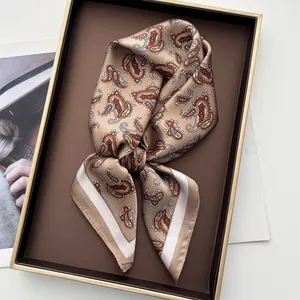 Detailed view of champagne paisley silk scarf featuring satin texture in a gift box