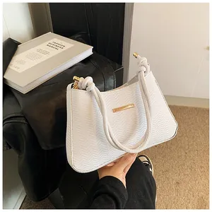Detail of white underarm bag featuring V-shaped texture and gold metal accents