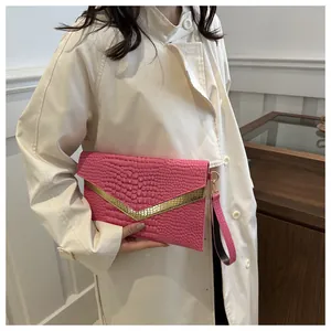 Close-up of pink crocodile pattern envelope clutch with gold V-metal trim and wristlet