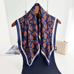 Detailed shot of dark blue paisley silk scarf draped on a wooden hanger for styling