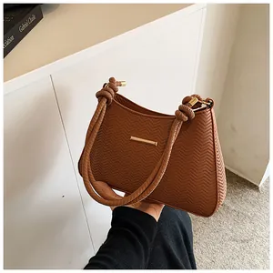 Close-up of brown underarm bag with V-shaped woven texture and knotted shoulder strap