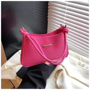 Detailed close-up of rose red knit shoulder bag featuring unique wave texture and knot handle