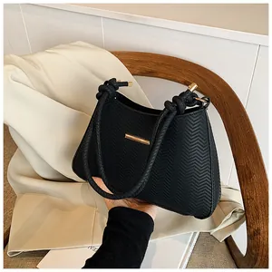 Detailed close-up of a black textured shoulder bag with rope handle and gold accents