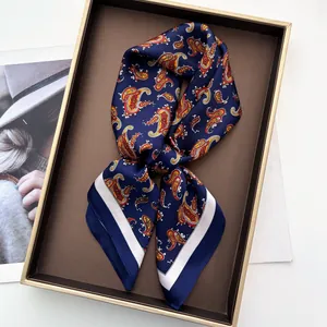 Close-up of a navy silk square scarf with vintage paisley print on a display tray