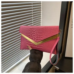 Detail of pink crocodile embossed envelope clutch with gold V-trim and wrist strap
