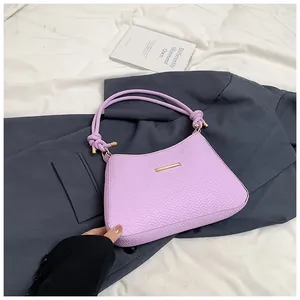 Close-up of lavender underarm bag with V-quilted texture and gold bar detail on blazer