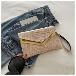 Detail of light pink crocodile pattern envelope clutch with golden V-shaped trim and wristlet