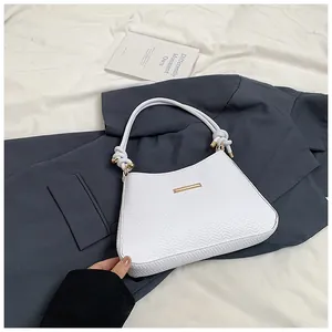 Detail of white textured fabric handbag with rope handle on navy blazer background