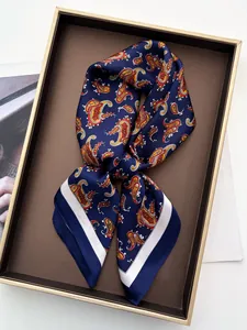 Detail view of a luxury navy blue paisley silk scarf elegantly folded in a premium gift box