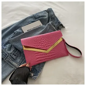 Detail shot of pink crocodile pattern envelope clutch with gold metallic trim accents