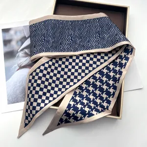 Detail of a navy silk scarf with wave, checkerboard and houndstooth patterns in a gift box