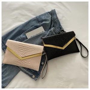 Detail of crocodile embossed faux leather envelope clutches with golden V-shaped metal trim