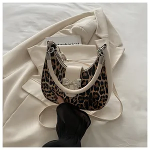 Dettaglio borsa a mezzaluna leopardata con fibbia a fiocco argento e finiture in crema