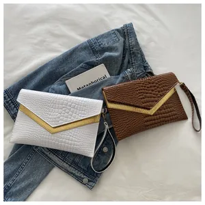 Flat lay of crocodile pattern envelope clutch bags with gold V-metal trim and wristlet
