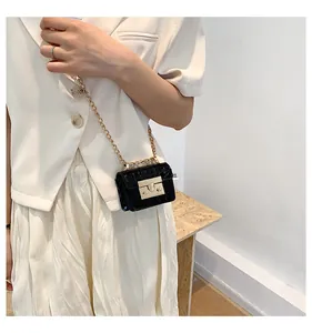 Detail of mini black crossbody bag with stone texture, gold chain and metal lock
