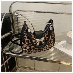Borsa a spalla leopardata con fibbia a fiocco argento su scaffale moderno