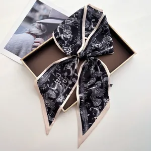 Elegant black faux silk scarf with mythical bird print on a decorative golden tray