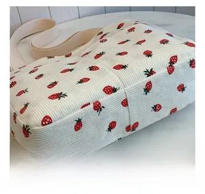 Detail view of corduroy tote bag showing strawberry print and durable stitched seams