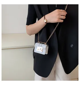 Mini stone-textured crossbody bag with gold chain strap shown on professional attire