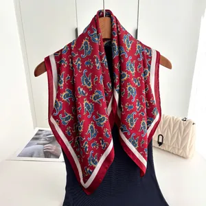 Vintage red paisley silk square scarf with blue patterns and ivory border on a hanger
