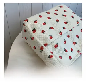 Close-up of white corduroy tote bag featuring a red strawberry print and soft texture