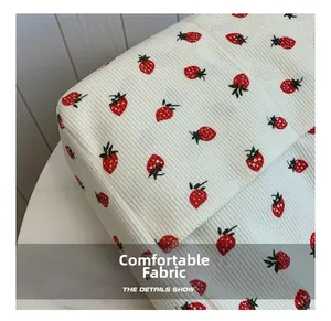 Close-up of white corduroy tote bag featuring delicate red strawberry embroidery