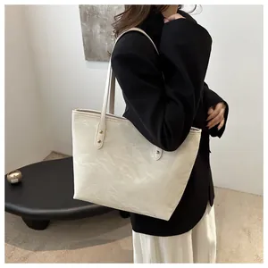 Detail of white wrinkled PU leather tote bag with gold rivets on shoulder strap