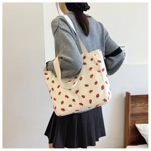 Detail of strawberry print corduroy tote bag showing side pocket and soft fabric texture