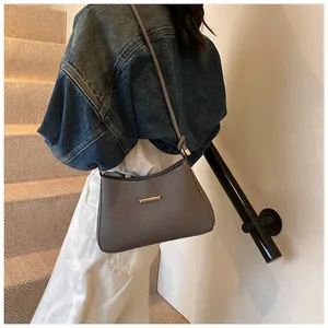Fashionable grey shoulder bag with gold hardware and knotted strap shown on model