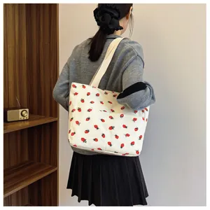 Detailed view of white corduroy tote bag with strawberry print and external pocket