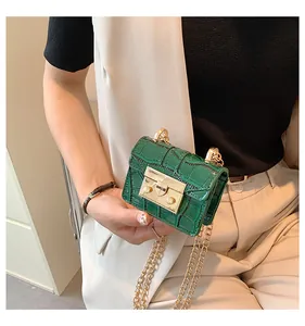 Close-up of dark green crocodile texture mini bag with golden chain and square clasp