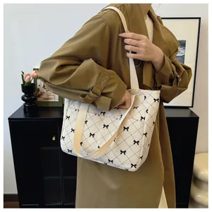 Detail of white corduroy tote bag with black argyle pattern and bow embroidery details