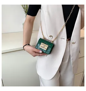 Detail of dark green crocodile texture mini bag with golden chain and metal clasp