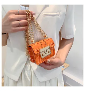 Detailed macro of orange crocodile pattern mini bag with bold golden chain strap