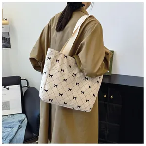 Detail of large corduroy tote bag with bow print and quilted pattern on shoulder