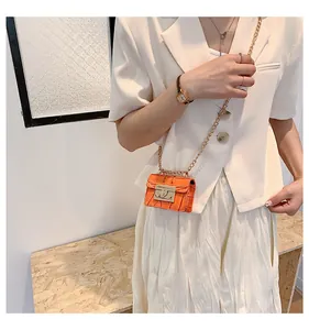 Detail of orange crocodile texture mini bag with gold chain strap and metal lock