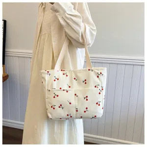 Detail of cream corduroy tote bag with red cherry prints and front utility pockets