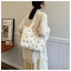 Detail of corduroy tote bag featuring red cherry patterns and front pocket on the side